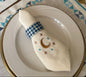 Elegant table setting with decorative napkins, cutlery, and tableware on a patterned tablecloth.